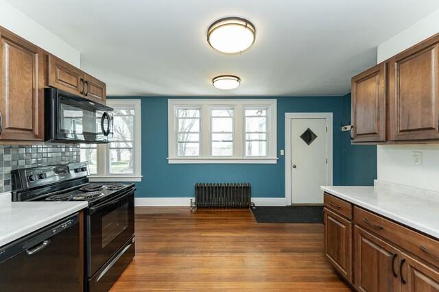 kitchen with radiator heating unit, black appliances, light countertops, and baseboards