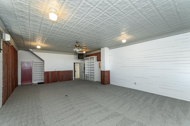 interior space featuring wood walls, carpet floors, a ceiling fan, a wainscoted wall, and a wall mounted AC