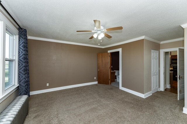 unfurnished bedroom with radiator, a textured ceiling, multiple windows, carpet floors, and ornamental molding