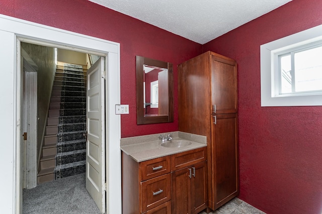 bathroom with vanity, a textured wall, and a textured ceiling