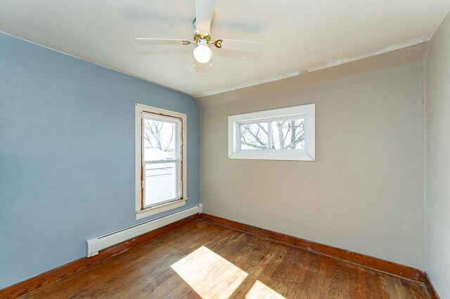 unfurnished room with a baseboard radiator, dark wood finished floors, baseboards, and a ceiling fan
