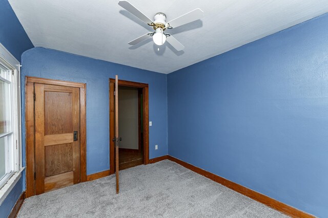 unfurnished bedroom featuring baseboards, carpet, a ceiling fan, and multiple windows