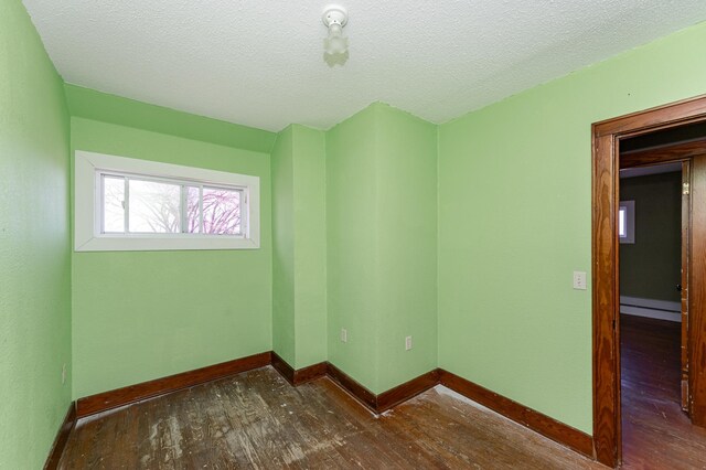 spare room with hardwood / wood-style flooring, baseboards, a textured ceiling, and baseboard heating