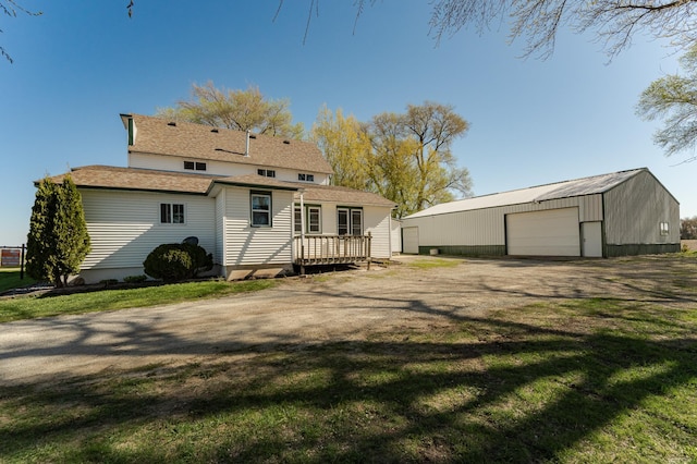 back of property with an outbuilding, a garage, a yard, and a deck