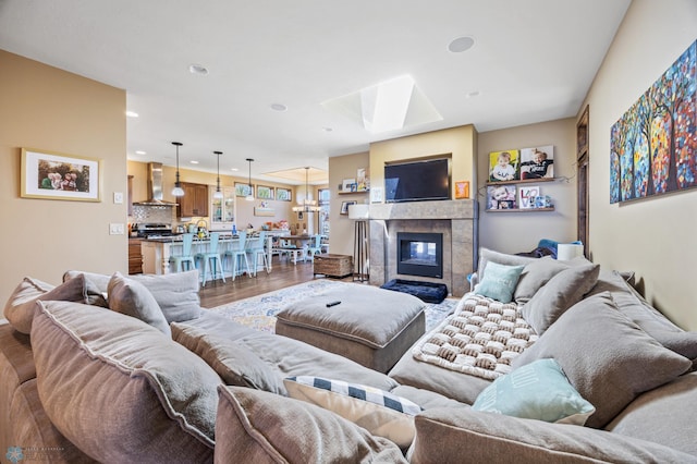 living room with a skylight, wood finished floors, recessed lighting, and a tiled fireplace
