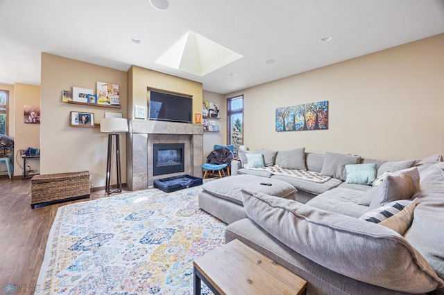 living room with a skylight, wood finished floors, a fireplace, baseboards, and recessed lighting