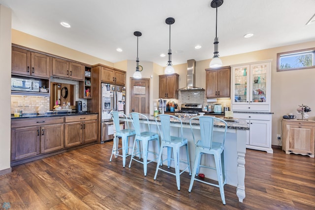 kitchen with wall chimney range hood, appliances with stainless steel finishes, backsplash, dark wood-style flooring, and recessed lighting