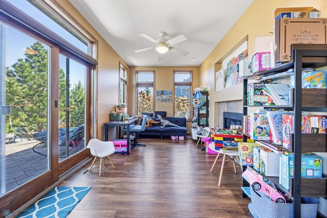 playroom with hardwood / wood-style floors, ceiling fan, and a tile fireplace