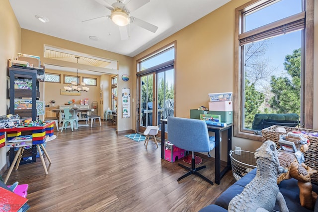 office space featuring plenty of natural light, wood finished floors, a chandelier, and a ceiling fan