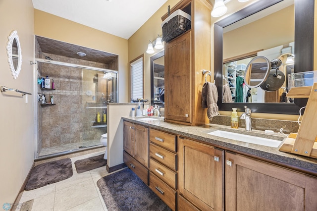 bathroom with a stall shower, toilet, double vanity, and tile patterned floors