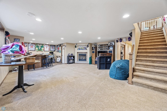 finished below grade area with carpet flooring, stairs, recessed lighting, and a fireplace