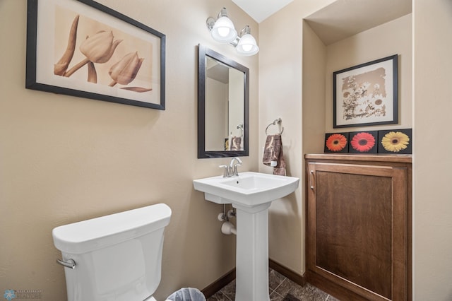 half bathroom featuring toilet, baseboards, and a sink