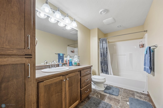 bathroom featuring toilet, shower / bathtub combination with curtain, vanity, and stone finish floors