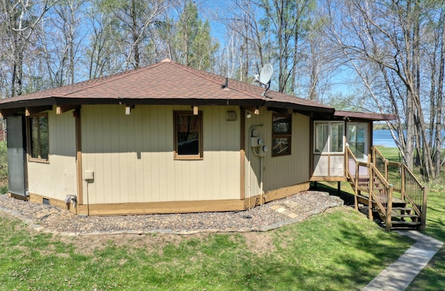view of home's exterior featuring roof with shingles and a yard