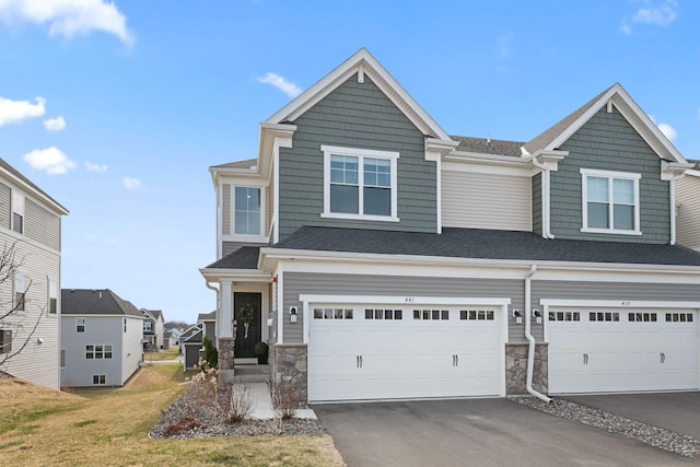 view of front of home with stone siding, aphalt driveway, and an attached garage