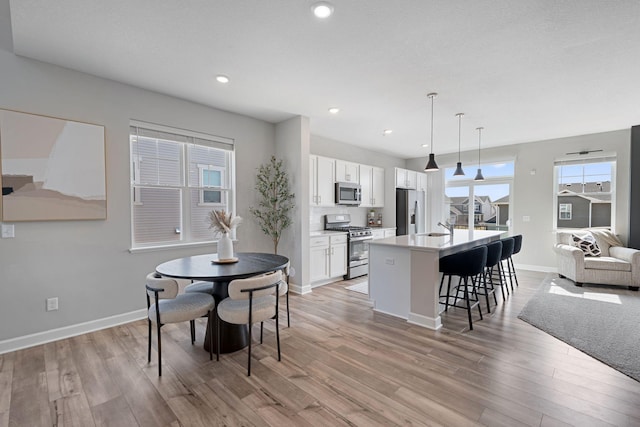 dining room with light wood-style flooring, baseboards, plenty of natural light, and recessed lighting