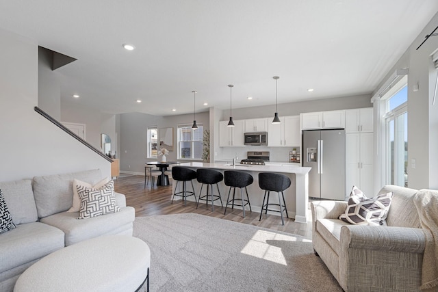 living room featuring baseboards, stairs, light wood-style floors, and recessed lighting