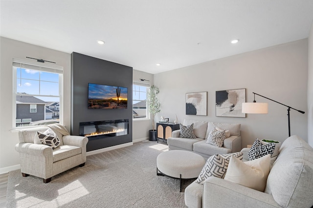 carpeted living area featuring baseboards, a glass covered fireplace, and recessed lighting