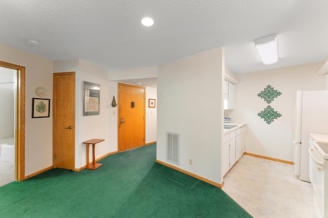 kitchen featuring white cabinets, range, light countertops, a textured ceiling, and light colored carpet