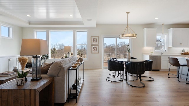 living area with light wood finished floors, a tray ceiling, and recessed lighting