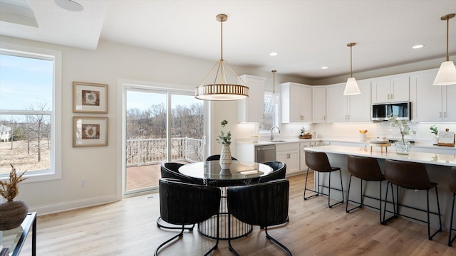 dining space with light wood-style floors, plenty of natural light, baseboards, and recessed lighting