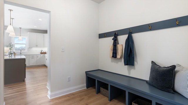 mudroom featuring light wood-style floors, baseboards, a sink, and recessed lighting