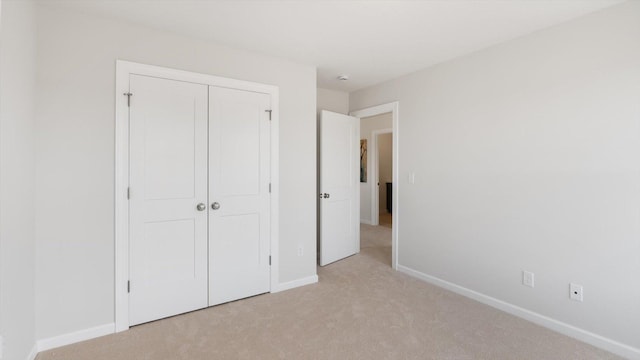 unfurnished bedroom featuring light colored carpet, baseboards, and a closet