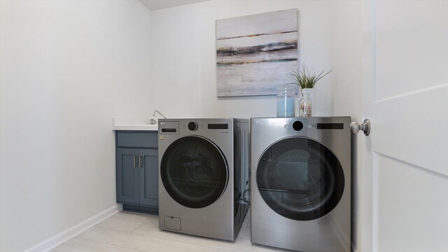 clothes washing area featuring cabinet space, washing machine and dryer, and baseboards