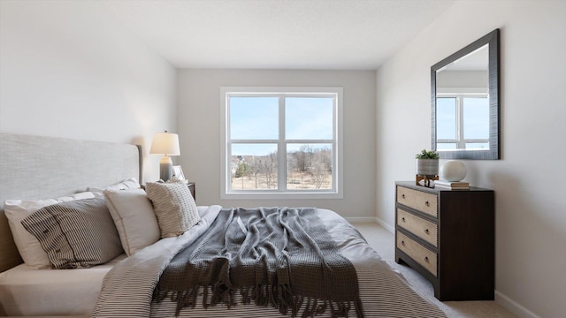 bedroom featuring multiple windows, light colored carpet, and baseboards