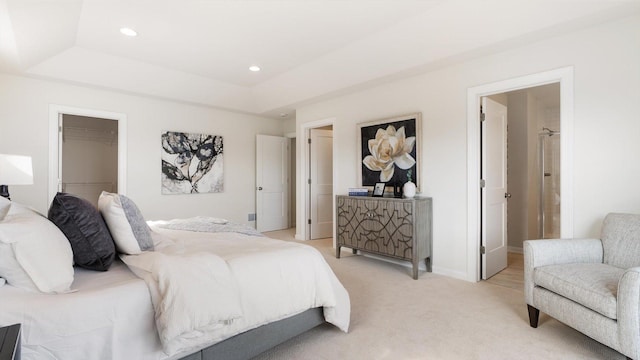 bedroom with a raised ceiling, light carpet, recessed lighting, a walk in closet, and baseboards