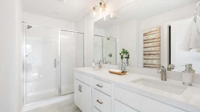 bathroom with a shower stall and double vanity