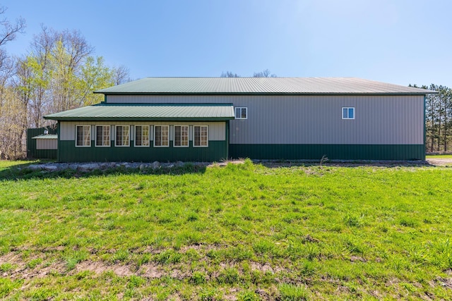 back of property featuring a yard and metal roof