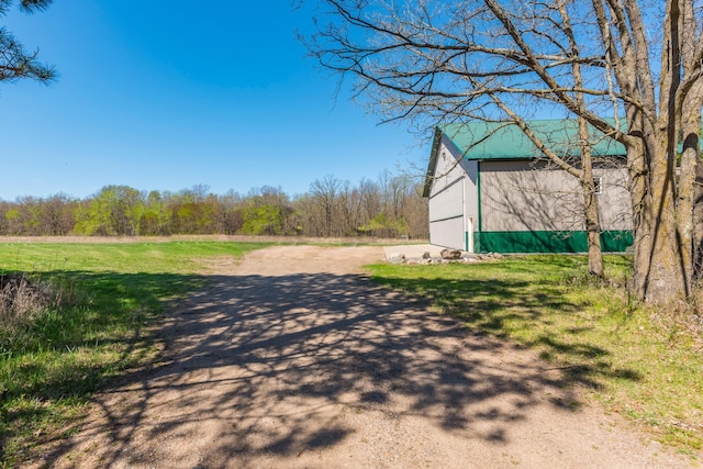 view of dirt / gravel driveway with a wooded view