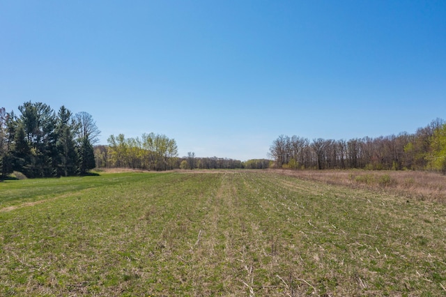 view of green lawn with a view of countryside and a forest view
