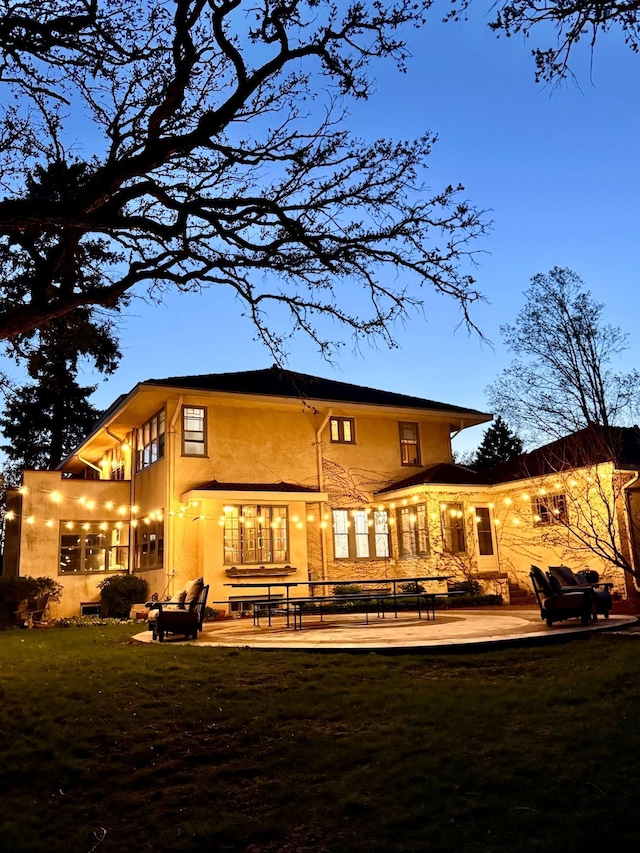 rear view of house featuring a patio, stucco siding, and a lawn