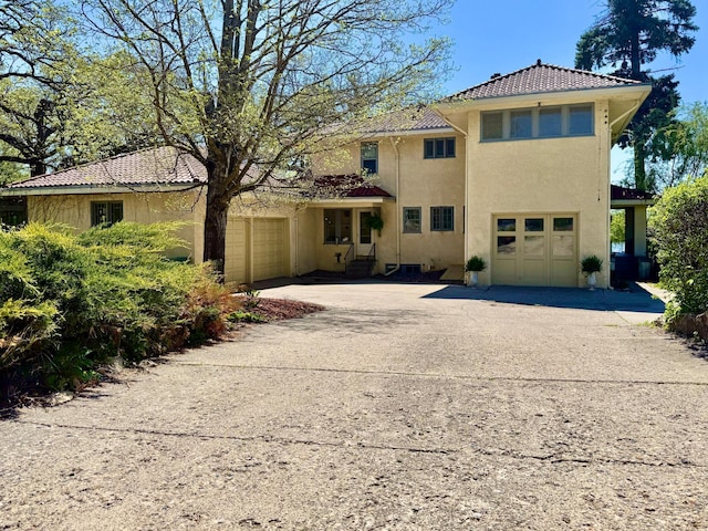 view of front facade featuring concrete driveway, stucco siding, a tile roof, and a garage