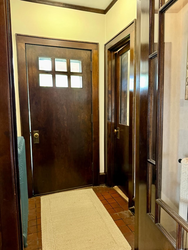 entryway with dark tile patterned floors and crown molding