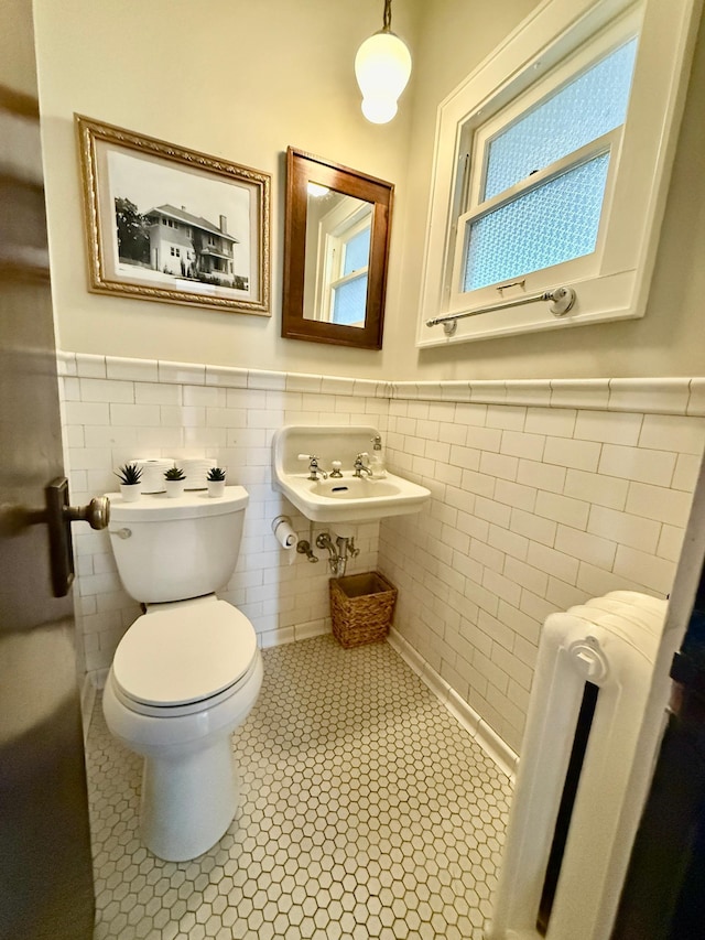bathroom featuring wainscoting, tile patterned flooring, toilet, tile walls, and a sink