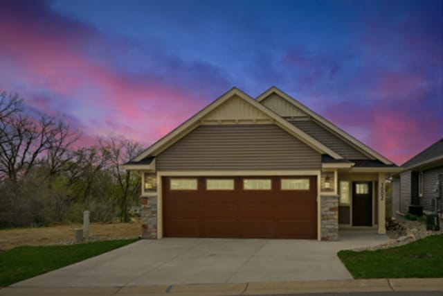 craftsman-style house featuring concrete driveway, stone siding, and a garage