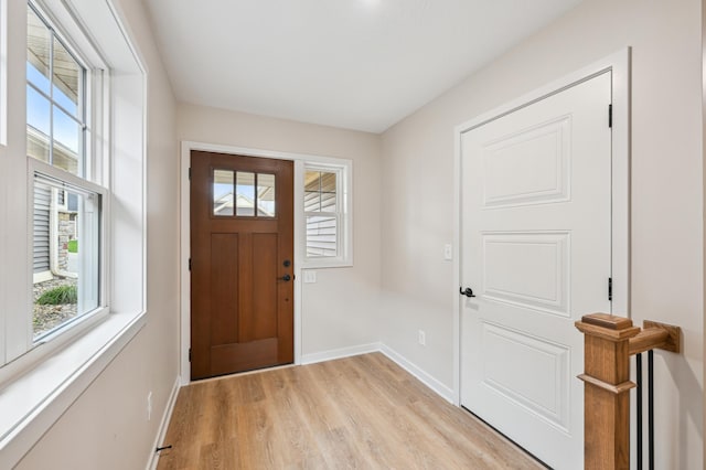 foyer entrance with plenty of natural light, light wood-type flooring, and baseboards