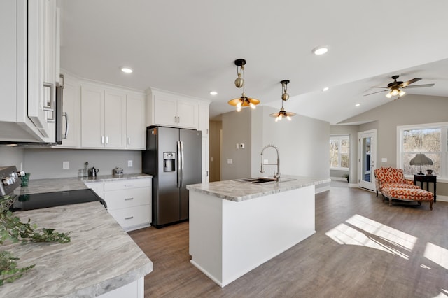 kitchen featuring dark wood finished floors, a sink, white cabinetry, open floor plan, and stainless steel appliances