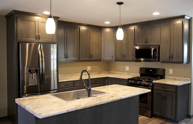 kitchen with stainless steel appliances, dark brown cabinetry, a sink, recessed lighting, and a kitchen island with sink