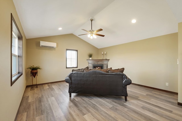 living room featuring lofted ceiling, a high end fireplace, light wood finished floors, a wall mounted AC, and a ceiling fan