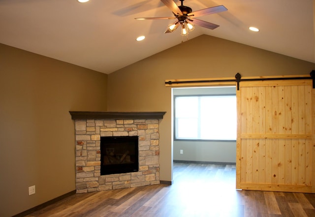 unfurnished living room with lofted ceiling, wood finished floors, recessed lighting, ceiling fan, and a stone fireplace