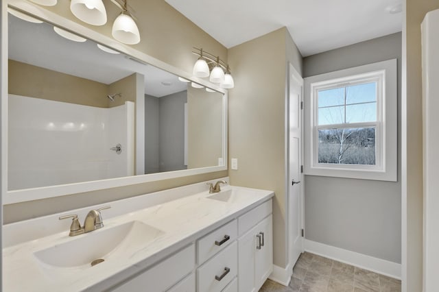 bathroom featuring a sink, double vanity, baseboards, and a shower