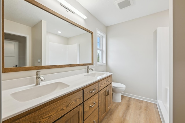 full bath with wood finished floors, toilet, double vanity, and baseboards