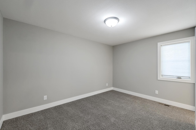 spare room with dark carpet and baseboards