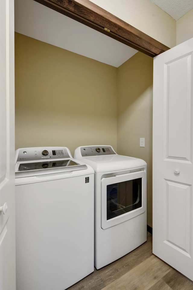 laundry area with washing machine and dryer and light wood-style flooring