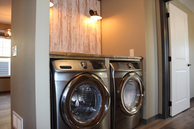 laundry room featuring wood finished floors, laundry area, visible vents, washing machine and clothes dryer, and baseboards