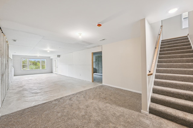 unfurnished living room featuring stairway and carpet flooring